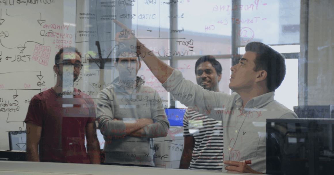 OPAL-RT engineers discussing real-time power system models at a whiteboard filled with electrical calculations.